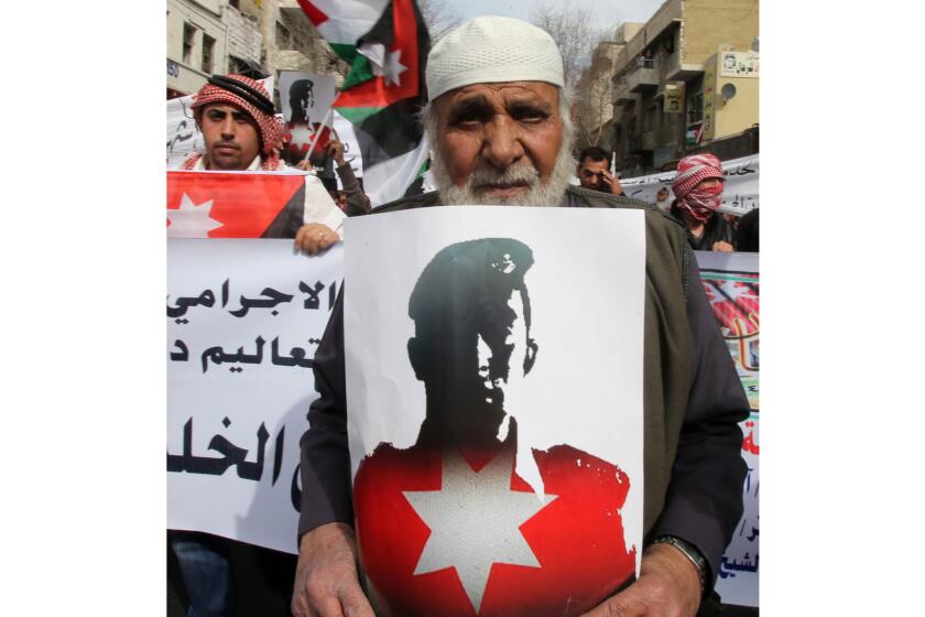 A demonstrator in Amman, Jordan, holds an image of pilot Moaz Kasasbeh, who was burned to death by Islamic State.