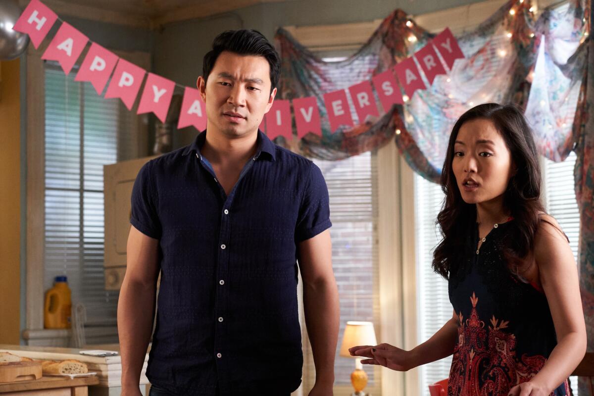 A man and a woman standing in front of a "Happy Anniversary" banner