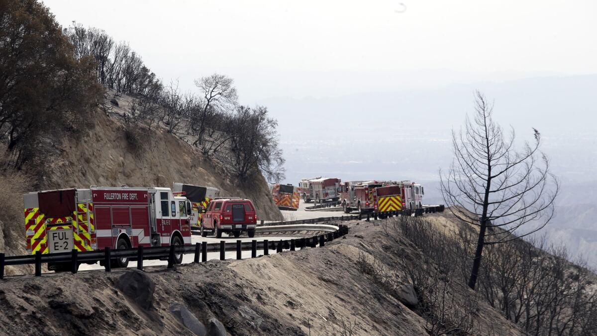 A convoy of fire trucks responds to an area affected by the Cranston fire in Mountain Center, Calif.