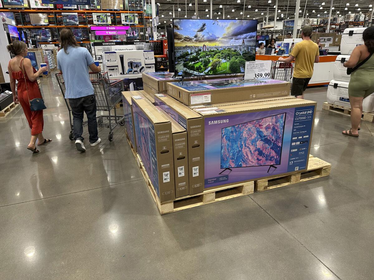Big-screen TVs are displayed in a warehouse store.