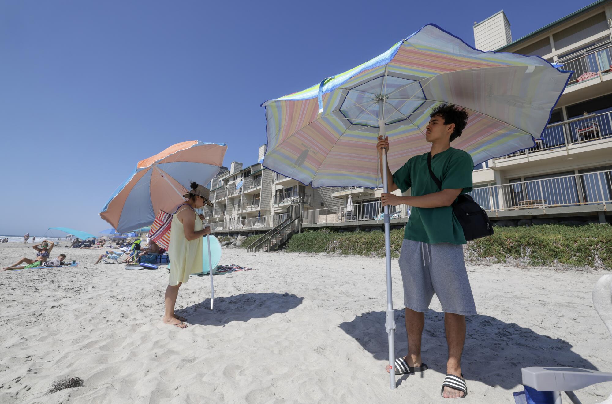 Escondido residents Rosa Anguiano and her son Christopher Rivera, 17, set up umbrellas on the beach in Carlsbad.