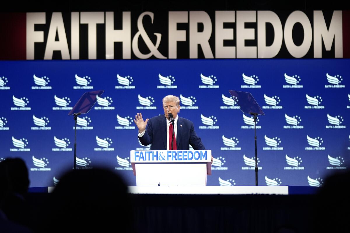 Donald Trump speaks under a large sign reading "Faith & Freedom," words repeated on a lectern and in logos in the background