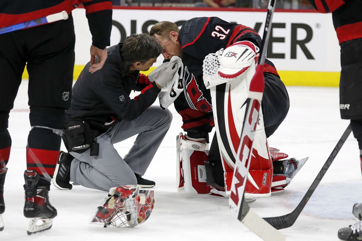 Carolina Hurricanes head athletic trainer Doug Bennett examines goaltender Antti Raanta (32) during the first period of Game 2 of the team's NHL hockey Stanley Cup first-round playoff series against the Boston Bruins in Raleigh, N.C., Wednesday, May 4, 2022. (AP Photo/Karl B DeBlaker)