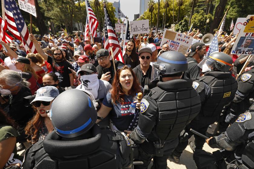 SACRAMENTO,CA-Alicia Cruz. center, of El Grove, California takes part in a protest really at the California State Capitol. She said she was there to protect civil liberties, the future for her children, and future livelihoods. CHP officers wearing riot gear were brought in to use the protesters off of the capitol grounds during a protest rally held on Friday, May 1, 2020. Over 1,500 people attending a rally at the capitol in Sacramento asking for the civil liberties and the opening of the economy, closed due to the coronavirus. (Carolyn Cole/Los Angeles Times)