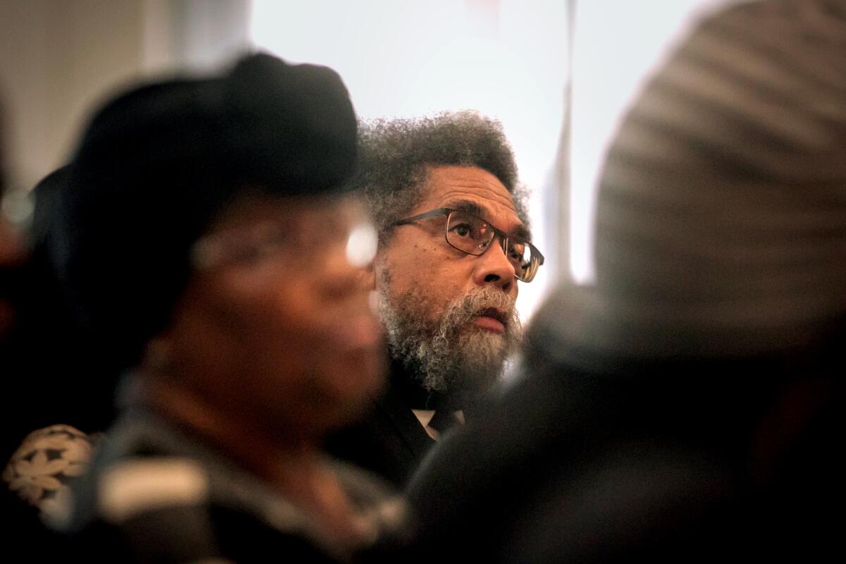 A close-up view of Cornell West, seen between other people.