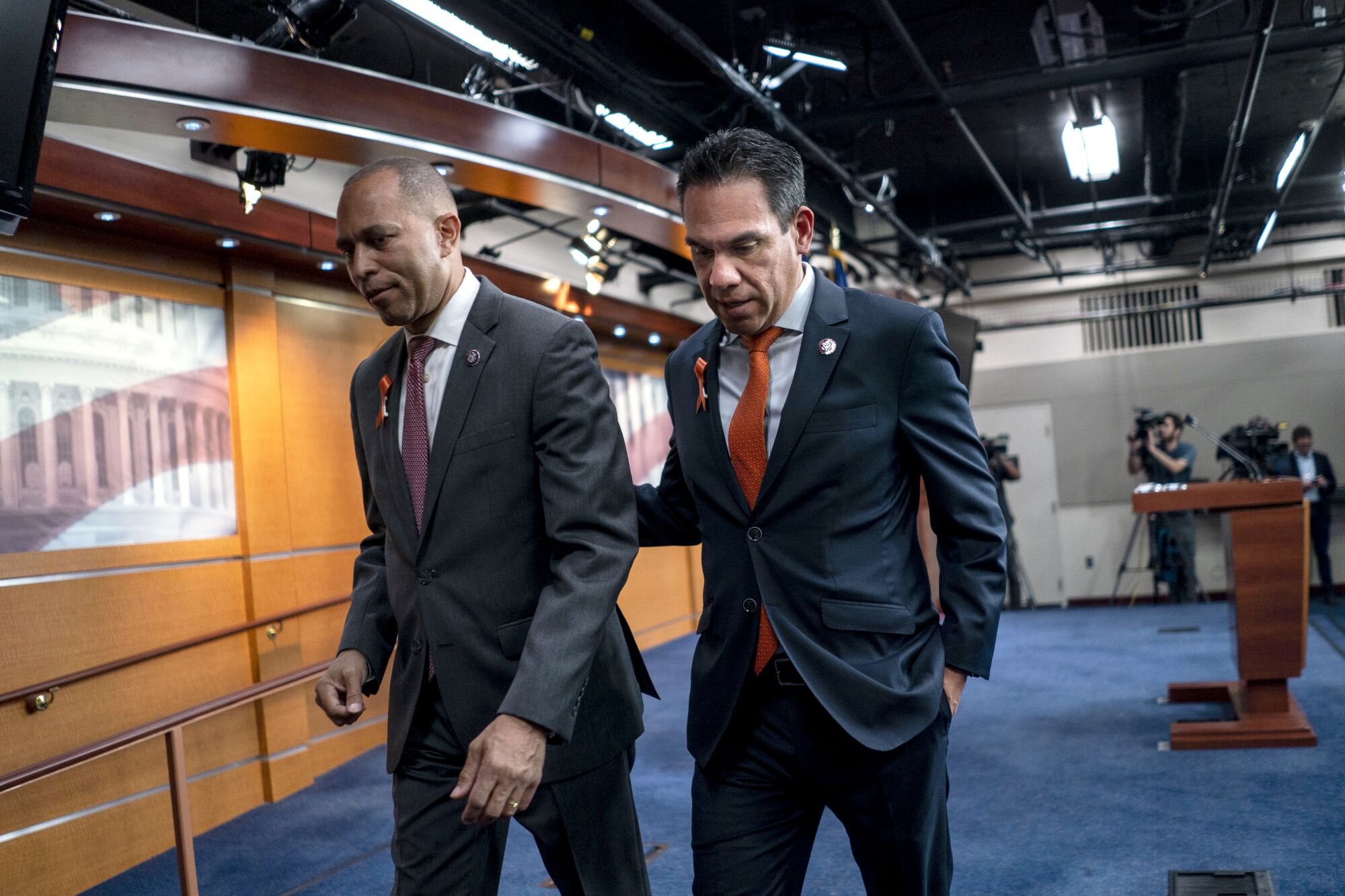 Pete Aguilar, right, places his hand on the back of Hakeem Jeffries as they walk together near a press-conference stage