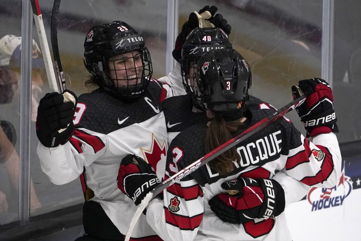 FILE - Canada's Marie-Philip Poulin, left, is congratulated by teammates Jocelyne Larocque (3) and Blayre Turnbull (40) after scoring the game-winning goal in overtime of a women's exhibition hockey game against the United States ahead of the Beijing Olympics, Dec. 15, 2021, in Maryland Heights, Mo. Poulin has been nicknamed `Captain Clutch' for an ability to score decisive goals on the world's biggest stage. (AP Photo/Jeff Roberson, File)