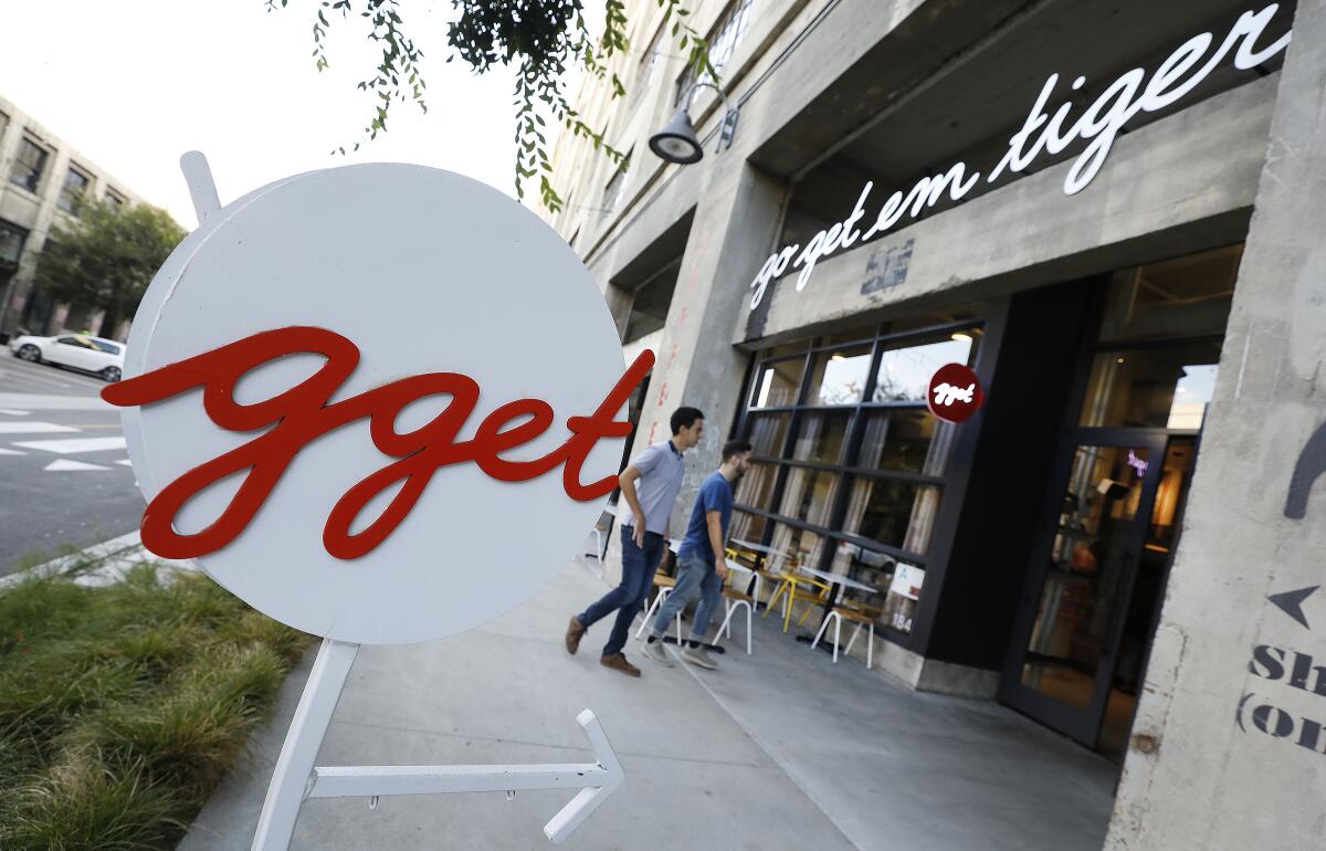 A circular sign with the letters "gget" appears on a sidewalk in front of a Go Get Em Tiger cafe.
