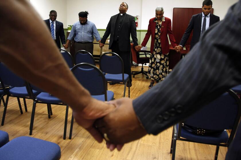 The Rev. John Cager, center, and other pastors and members of the Southern California Conference Ministerial Alliance, join hands in prayer at Ward AME Church.