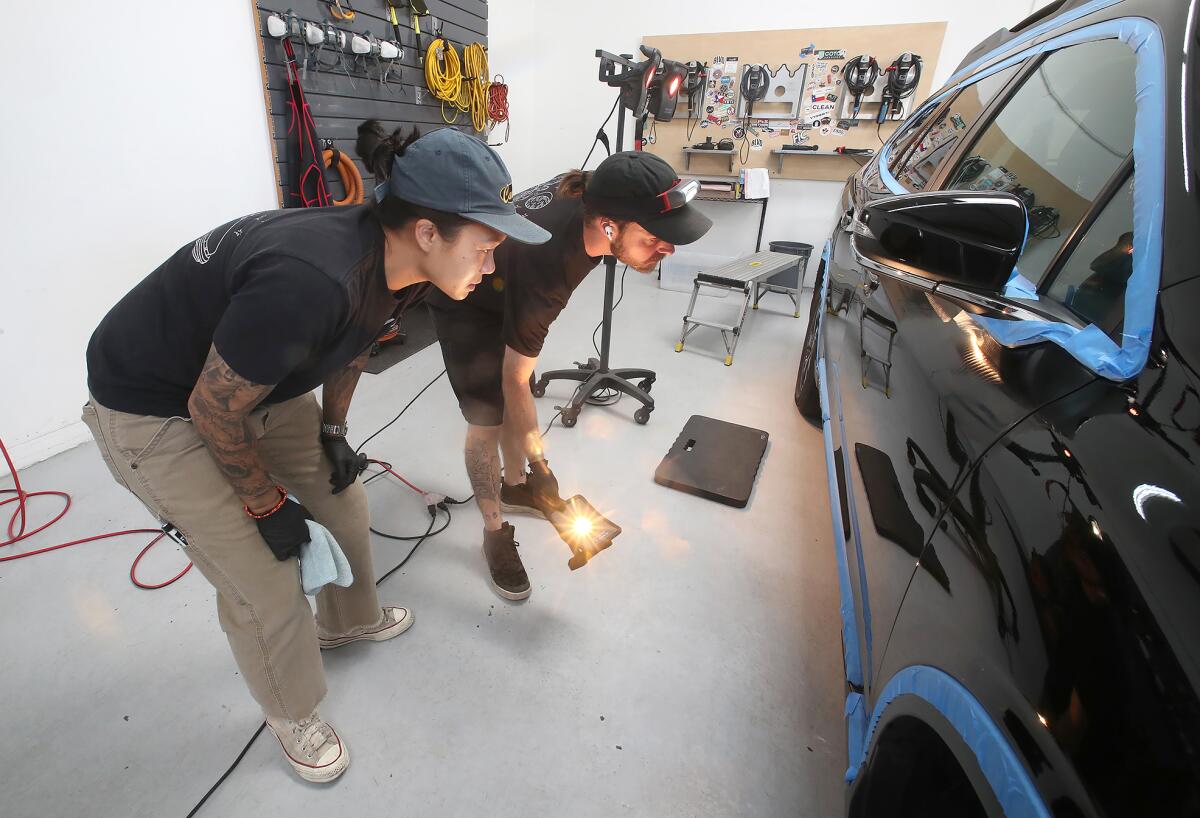 Jessica Tran and staff member Daulton Lantow, from left, inspect the details of a Subaru.