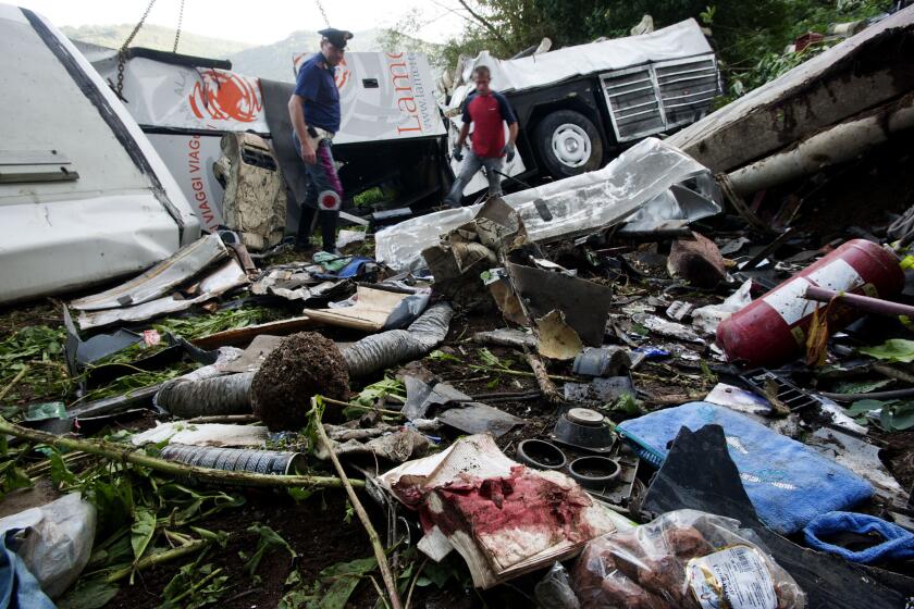 Rescuers stand in the wreckage of a bus which crashed off a highway near Avellino, in southern Italy.