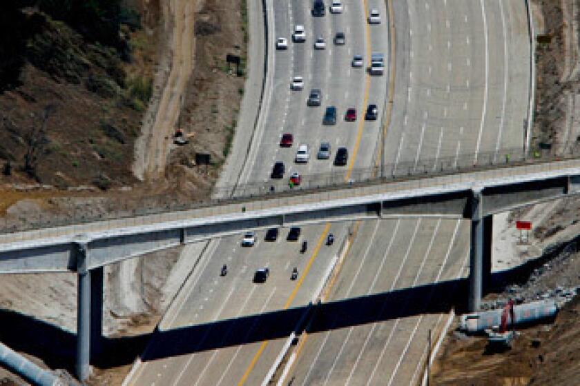 The first southbound cars, escorted by the California Highway Patrol, approach the Mulholland Drive bridge after the 405 Freeway was reopened following its closure for half the bridge to be demolished this weekend. The freeway opened about 17 hours earlier than anticipated.