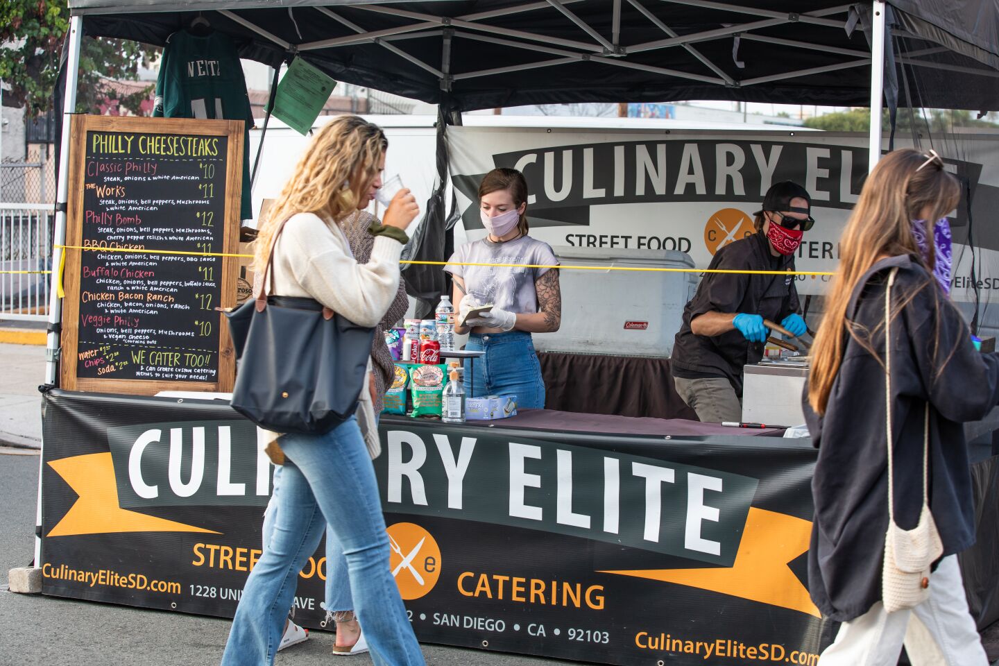 Marissa Kastelic and Kelin Jones, owner of Culinary Elite Street Food & Catering, work their booth at the Ocean Beach Farmers Market.