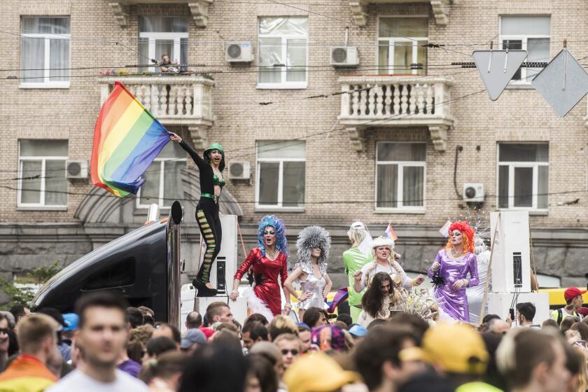 A gay and lesbian rights activist waves a rainbow flag during the annual Gay Pride parade, protected by riot police in Kiev, Ukraine, Sunday, June 17, 2018. Several thousand supporters of gay pride have held a march in Ukrainian capital that lasted about 20 minutes despite opponents attempts to block them. (AP Photo/Evgeniy Maloletka)