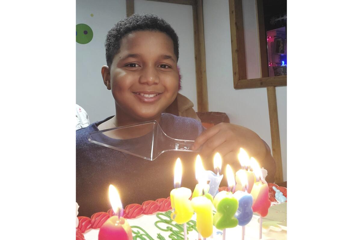 A smiling child looks over candles on a birthday cake