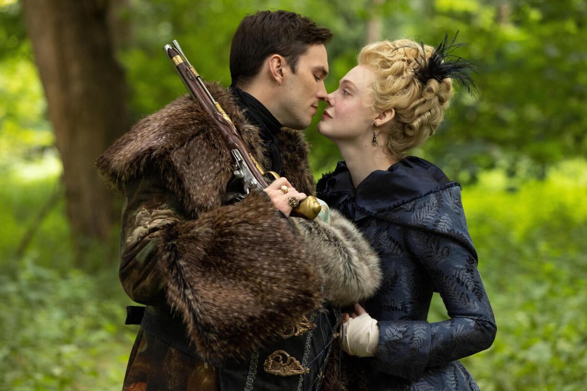 Nicholas Hoult brings his face close to Elle Fanning's while holding a gun in a forest in "The Great"