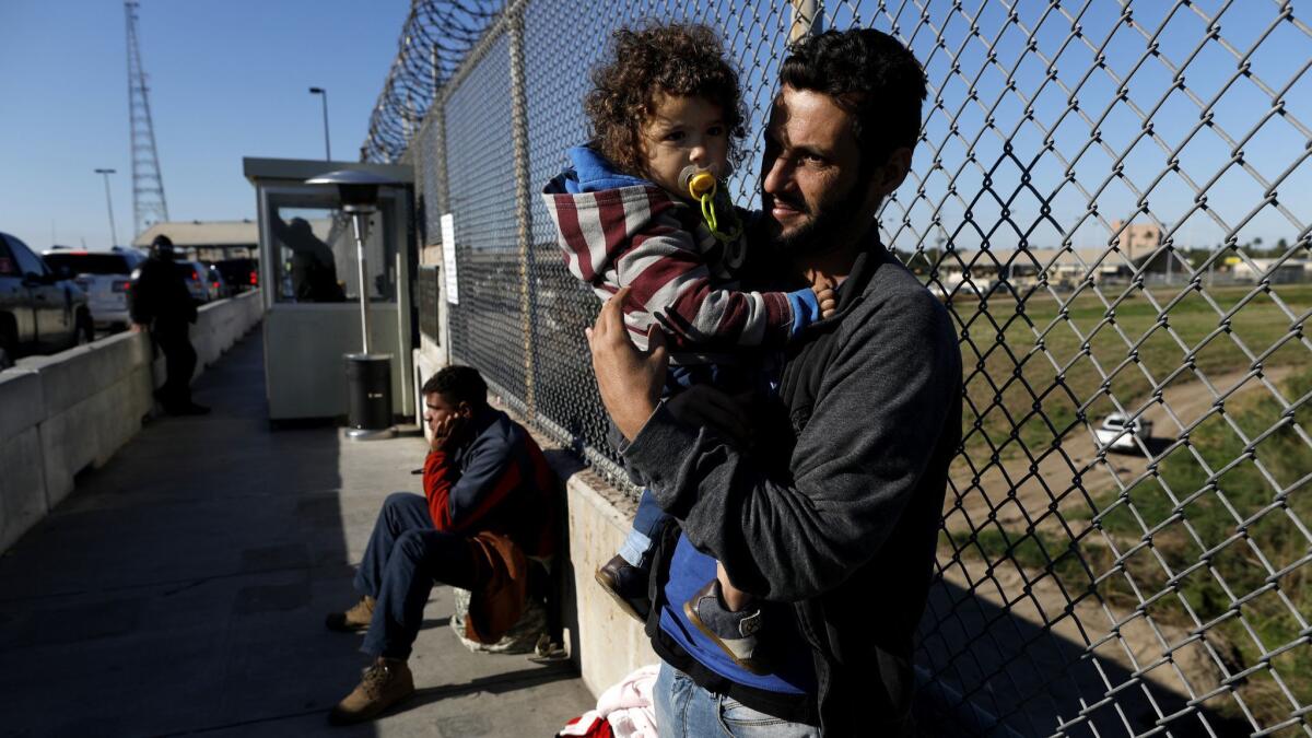 Political asylum seekers Elvis Gonzalez, 23, left, a Cuban from Havana, and Brazilians Robert Richard Braganca of Rio de Janeiro and son Mario, 18-months, camp out on the Matamoros and Brownsville International Bridge in Matamoros, Mexico.