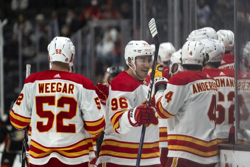 Calgary Flames left wing Andrei Kuzmenko (96) is congratulated for his goal against the Anaheim Ducks during the third period of an NHL hockey game Friday, April 12, 2024, in Anaheim, Calif. (AP Photo/Kyusung Gong)
