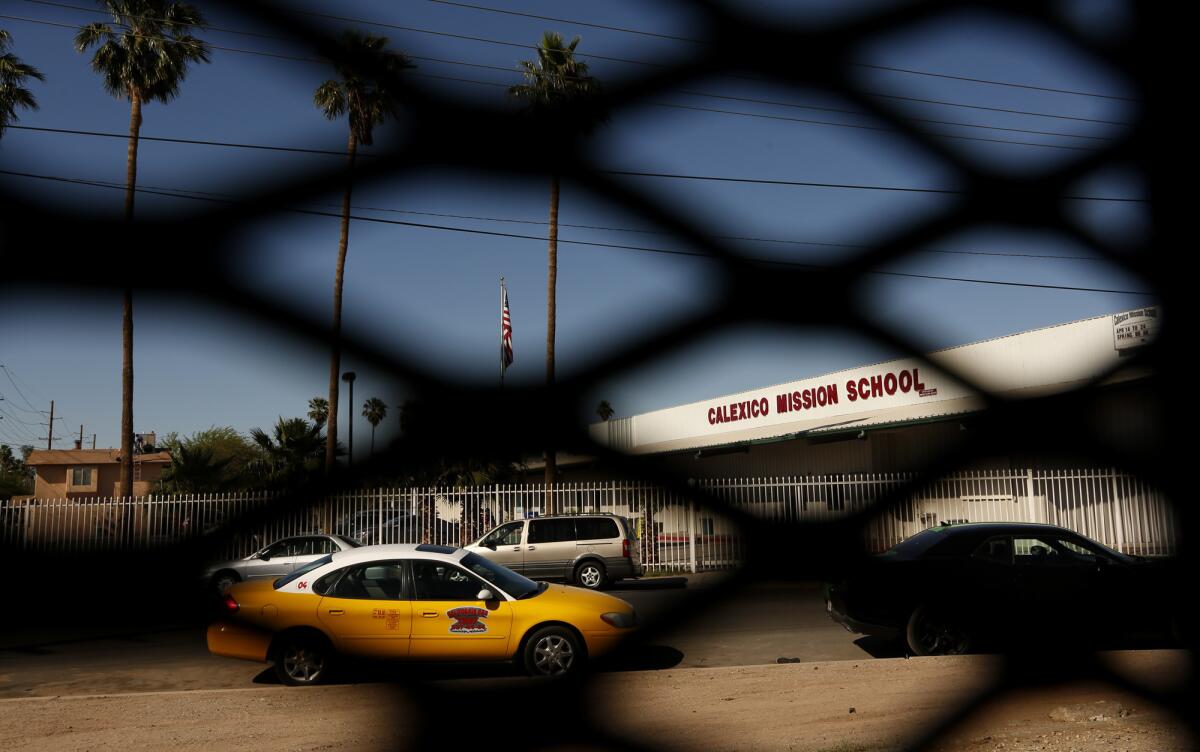 The Calexico Mission School, as seen from Mexico, is framed by a portion of the fence that borders California and Mexico. More Photos