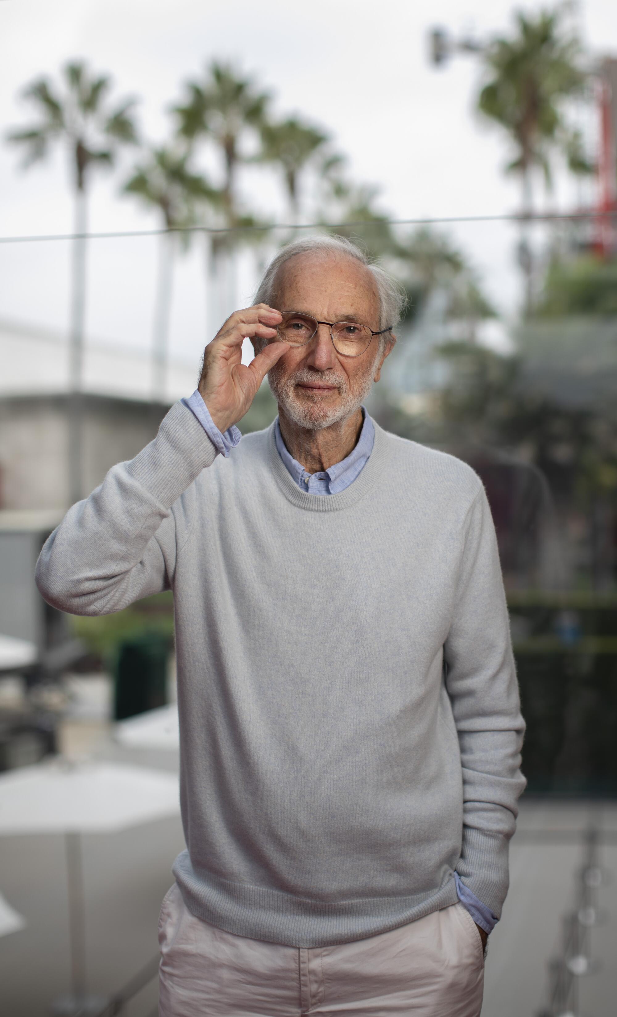 Renzo Piano, in a crewneck sweater, adjusts his eyeglasses.