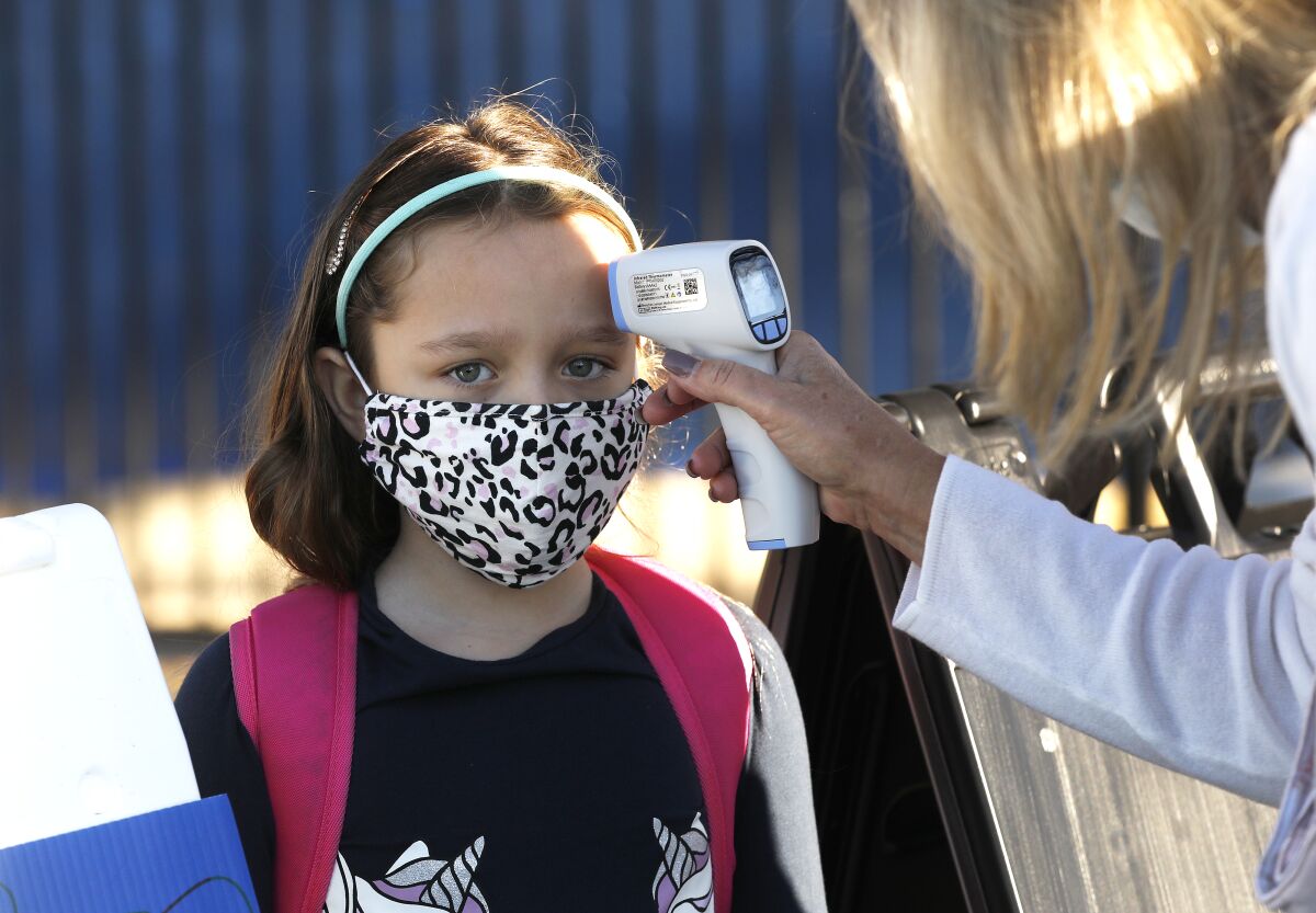 First-grader Lili McInerney has her temperature checked before entering Lupin Hill Elementary.