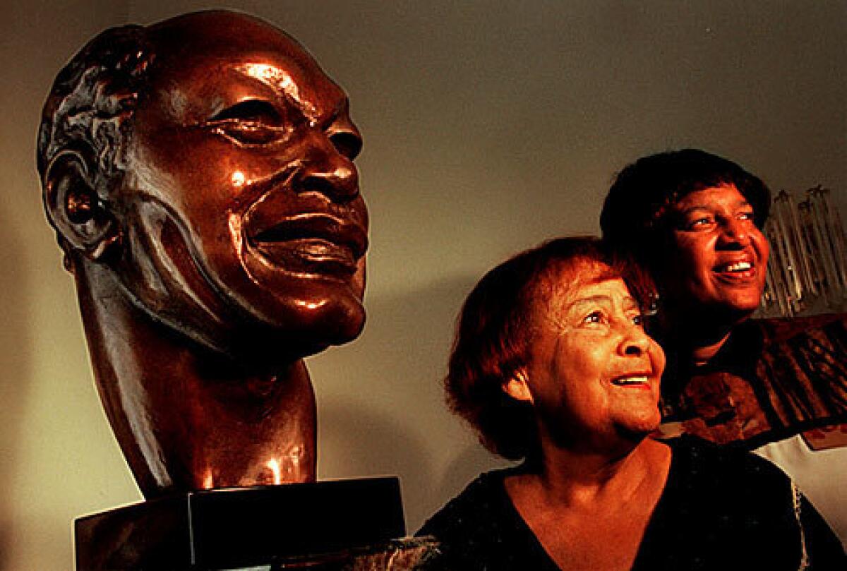 Ethel Bradley and her daughter Lorraine Bradley pose next to a bust of former Los Angeles Mayor Tom Bradley that the family donated to the African American Museum.