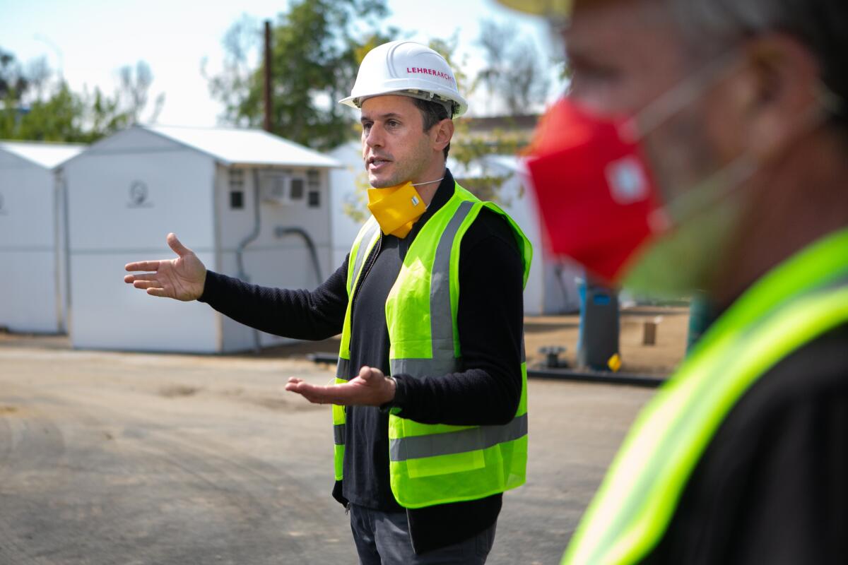 Architect Nerin Kadribegovic in a hard hat and yellow safety vest in the middle of a tiny village that is under construction