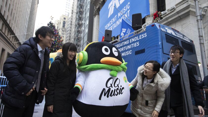 Tencent Music Entertainment employees pose with the QQ Music mascot in front of the New York Stock Exchange prior to the Chinese company's IPO on Dec. 12.