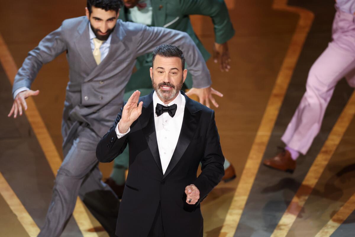 A man in a tux surrounded by dancers on a stage