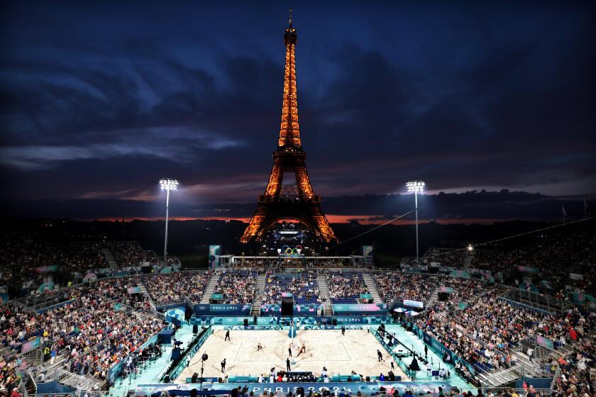The sun sets over the Eiffel Tower as the U.S. and Canada women beach volleyball teams compete in Paris Saturday.