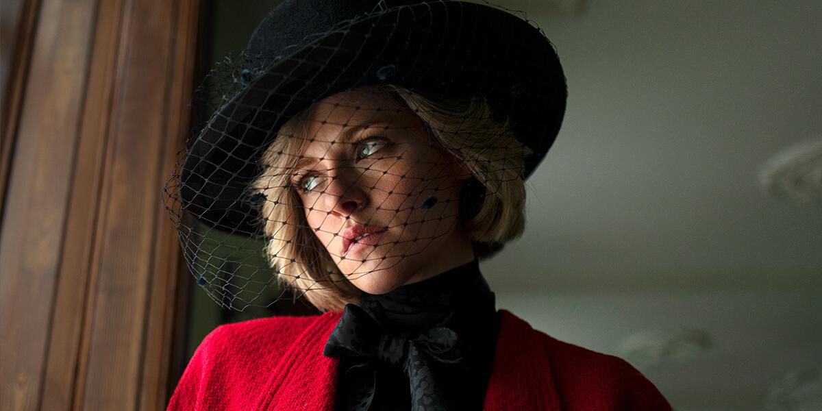 A woman in a red coat and black hat with a mesh veil over her face.