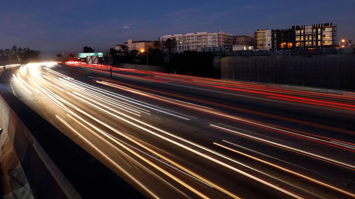 Traffic flows below a pair of affordable housing developments under construction next to the 110 Freeway at El Segundo Boulevard in Los Angeles.