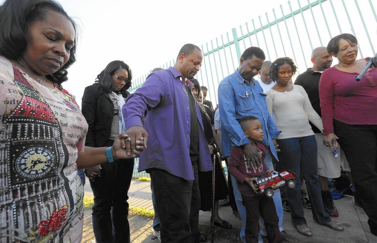 Community activist Najee Ali, in the purple shirt, prays during a vigil in memory of Latasha Harlins, a teen who was fatally shot by South L.A. shop owner Soon Ja Du in 1991.