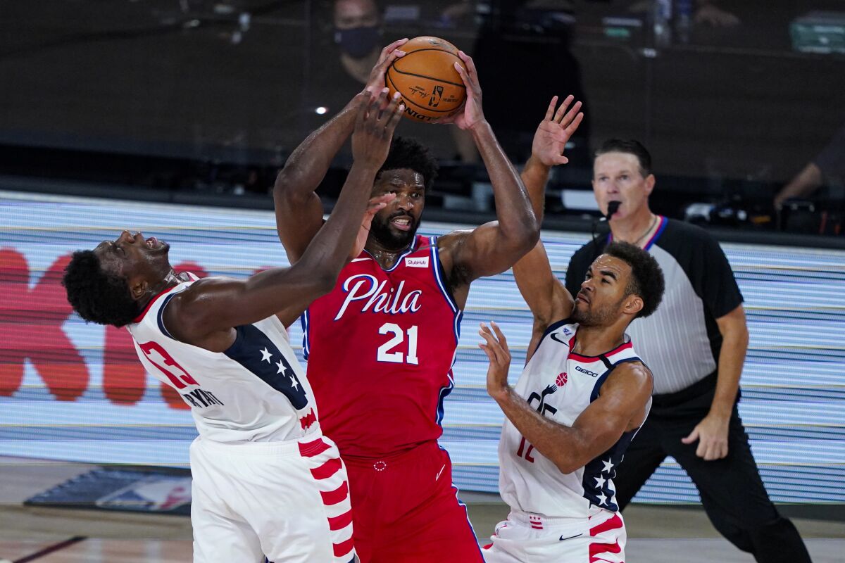 Washington Wizards center Thomas Bryant (13) and guard Jerome Robinson (12) tries to tie up Philadelphia 76ers center Joel Embiid (21) during the second half of an NBA basketball game Wednesday, Aug. 5, 2020 in Lake Buena Vista, Fla. (AP Photo/Ashley Landis)