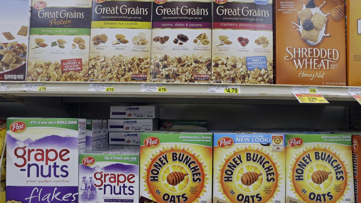 Post cereals are lined up on a grocery shelf. Post Holdings is buying MOM Brands Co., maker of Malt-O-Meal.