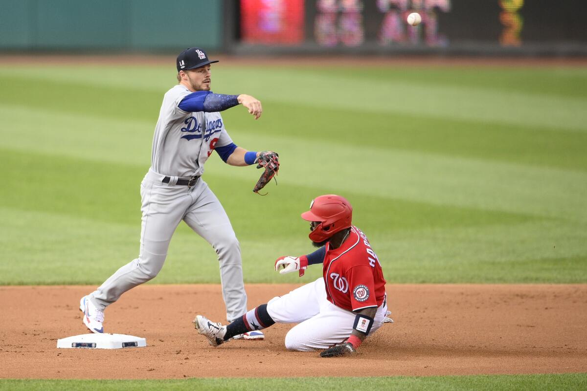 Dodgers shortstop Gavin Lux turns a double play in front of Washington's Josh Harrison during the first inning.