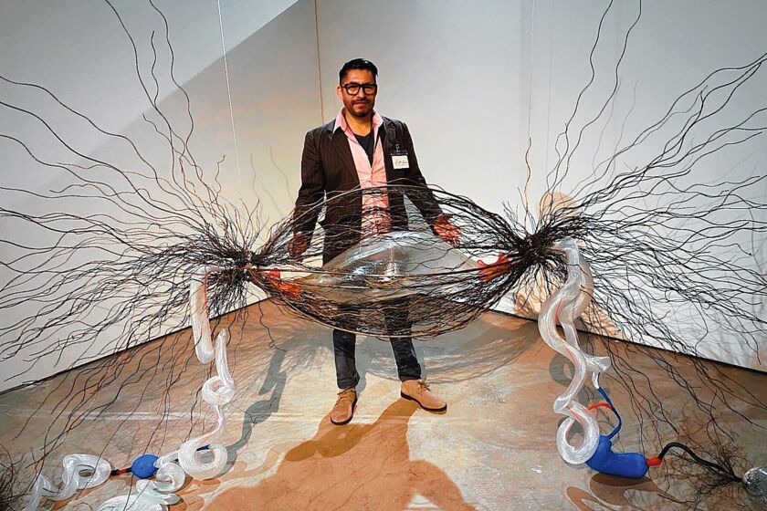 Glass artist Hugo Heredia Barrera, with his supersized cancer-infected cell, trapped in steel threads and connected by plastic DNA tubes to some still-healthy, clear-glass cells. 'Illumination: 21st century interactions with art, science and technology' is on exhibit through May 3, 2020 at San Diego Art Institute, 1439 El Prado in Balboa Park, San Diego. Hours: noon to 5 p.m. Tuesday-Sunday. (619) 236-0011. sandiego-art.org