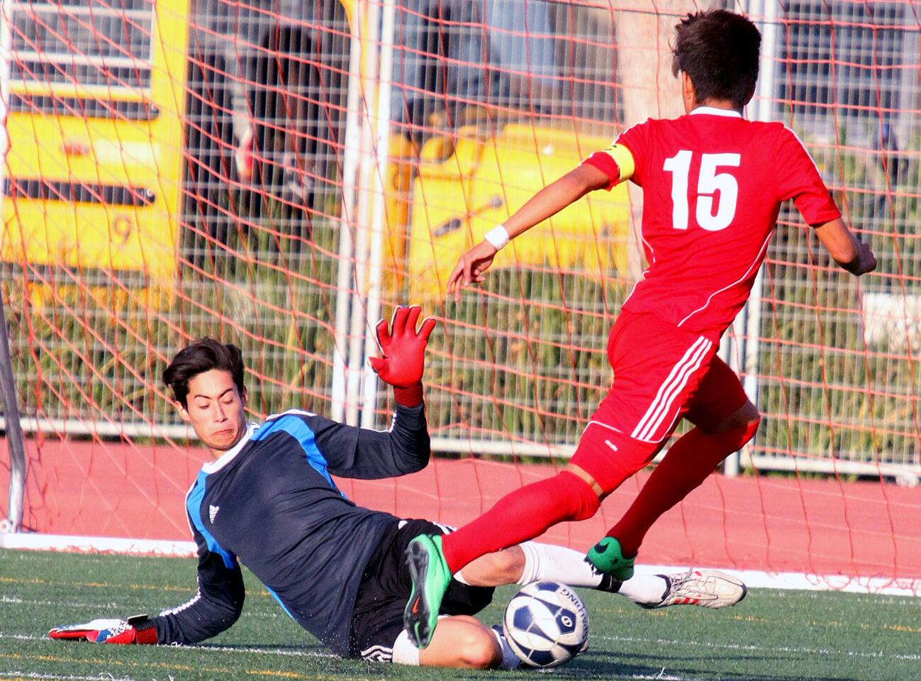 Burroughs' goal keeper Alberto Meir slides and kick saves the ball against Katella's Jose Troncoso (15) who was on a breakaway in a first-round CIF playoff boys soccer game at Burroughs High School in Burbank on Thursday, February 20, 2014. Burroughs lost the game 1-0.