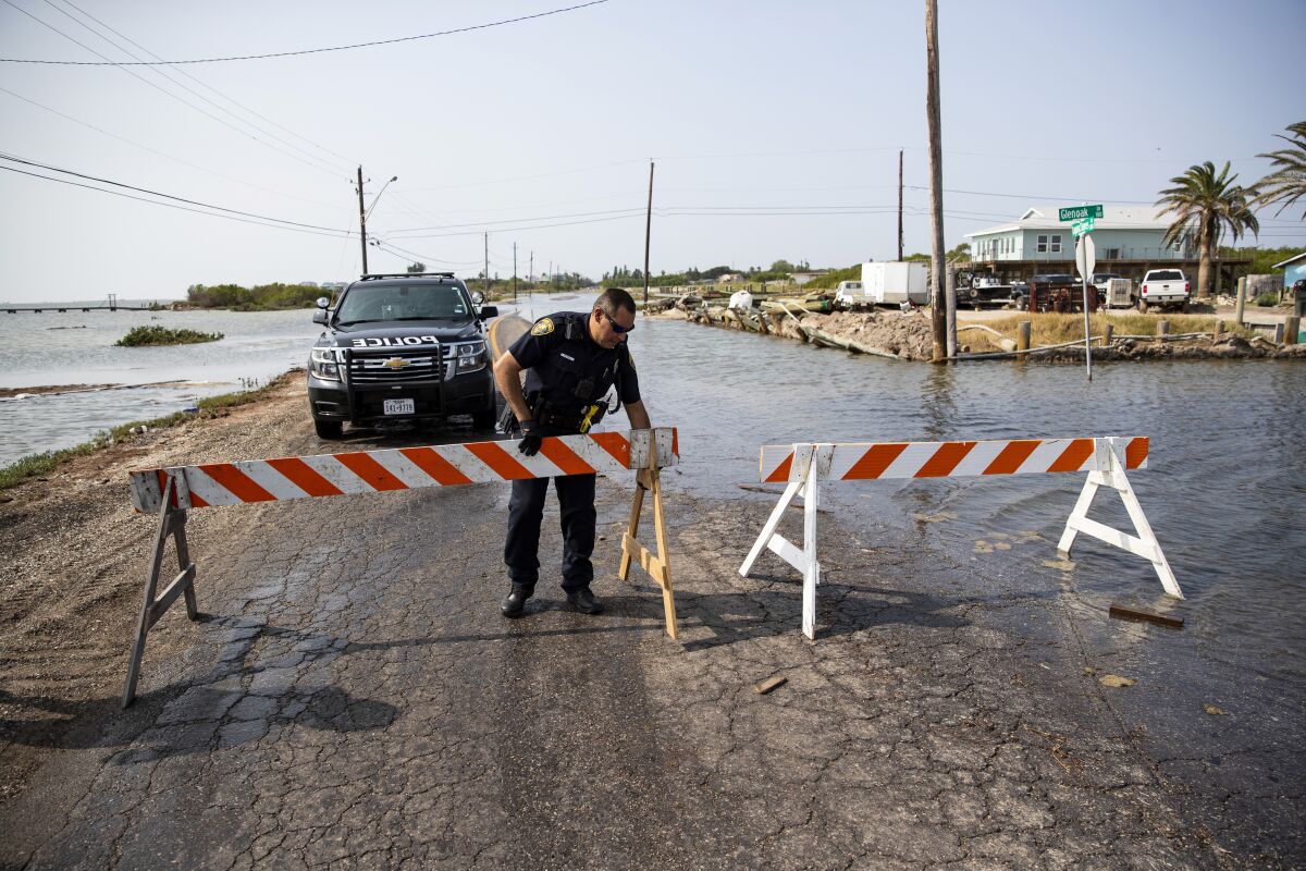 A police office places a barricade to close Laguna Shores Boulevard due to flooding on Sunday in Corpus Christi, Texas.