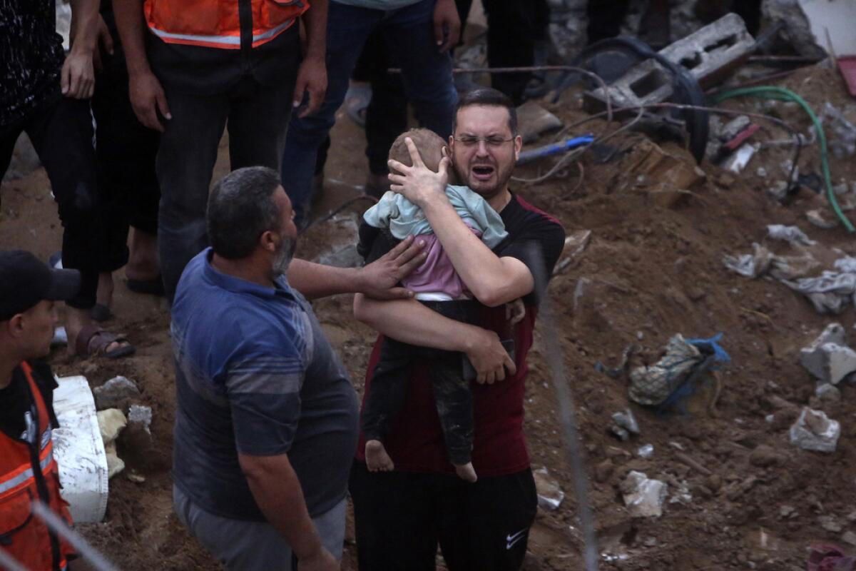 Un hombre palestino llora mientras sostiene en brazos a un bebé 