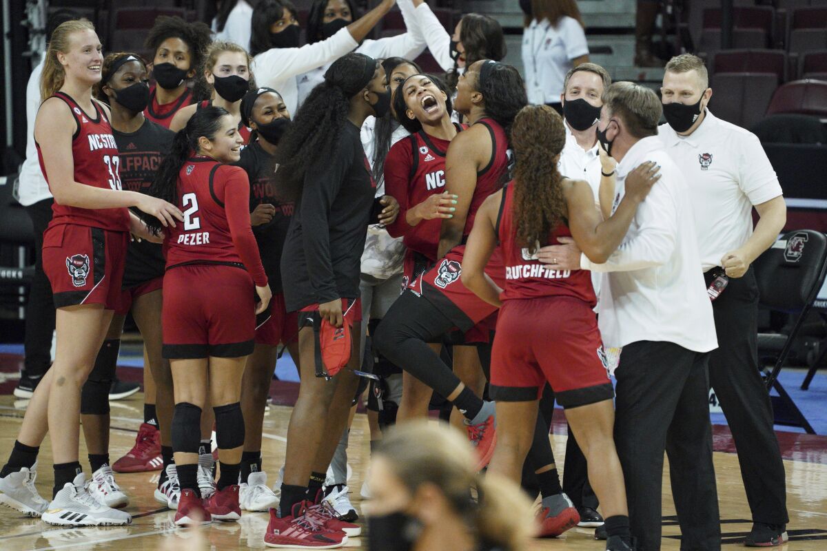 North Carolina State players celebrate with the coaching staff after an NCAA college basketball game against South Carolina Thursday, Dec. 3, 2020, in Columbia, S.C. (AP Photo/Sean Rayford)