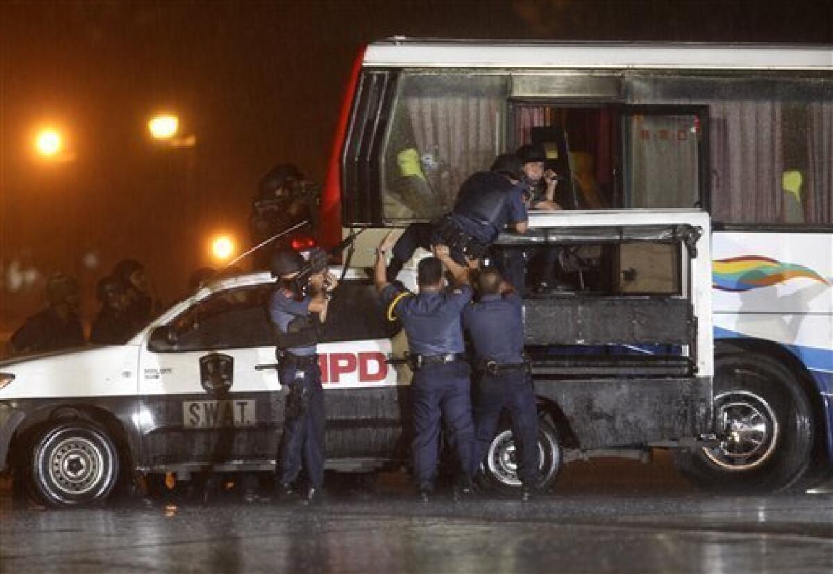 Police and SWAT members assault a tourist bus to rescue hostages at Manila's Rizal Park Monday Aug.23, 2010 in Manila, Philippines. Rolando Mendoza, a dismissed policeman armed with automatic rifle, seized the bus in Manila Monday with 25 people aboard, mostly foreign tourists in a bid to demand reinstatement, police said. Mendoza was killed along with an undetermined number of hostages. (AP Photo/Bullit Marquez)