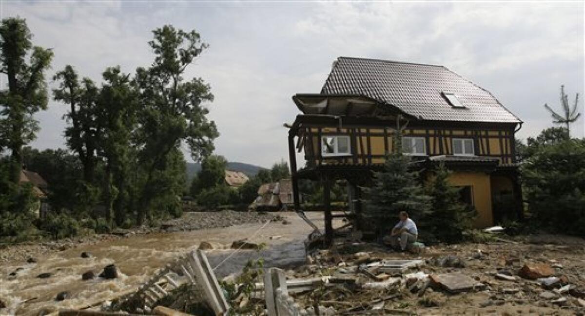 A resident sits by his destroyed house after a flash floods hit the town of Bogatynia, Poland, Sunday, Aug. 8, 2010. The flooding has struck an area near the borders of Poland, Germany and the Czech Republic. (AP Photo/Petr David Josek)