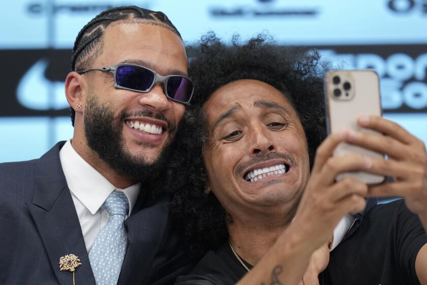 El atacante neerlandés Memphis Depay posa con Papi, un reportero de la televisión, en una rueda de prensa en la que fue presentado como jugador de Corinthians, el jueves 12 de septiembre de 2024, en Sao Paulo. (AP Foto/Andre Penner)