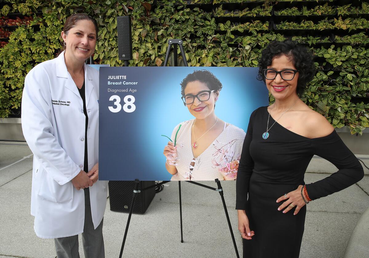 Amanda Schwer, M.D. and young patient Juliette Landgrave, 40, from left, stand next to poster pictures.