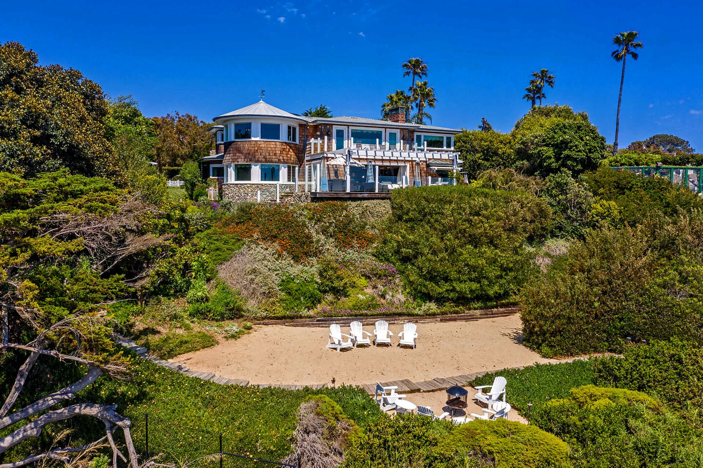This coastal Cape Cod overlooks the ocean from a bluff in Point Dume, descending to a stretch of private beach.