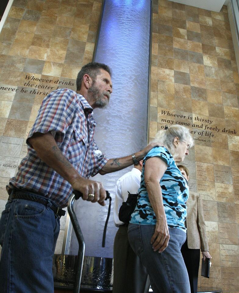 Donald Akers, of San Fernando, with a cane and using his friend Peggy Salazar's shoulder, walks to the exit of the hospital passed the newly dedicated Living Waters waterfall at the dedication of the waterfall in the lobby of the West Tower at Glendale Adventist Medical Center in Glendale on Thursday, March 14, 2013.
