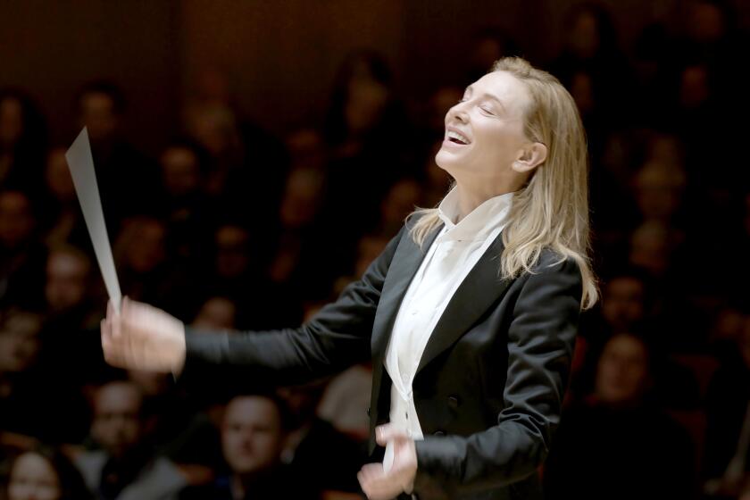 A blond woman in a suit conducting an orchestra