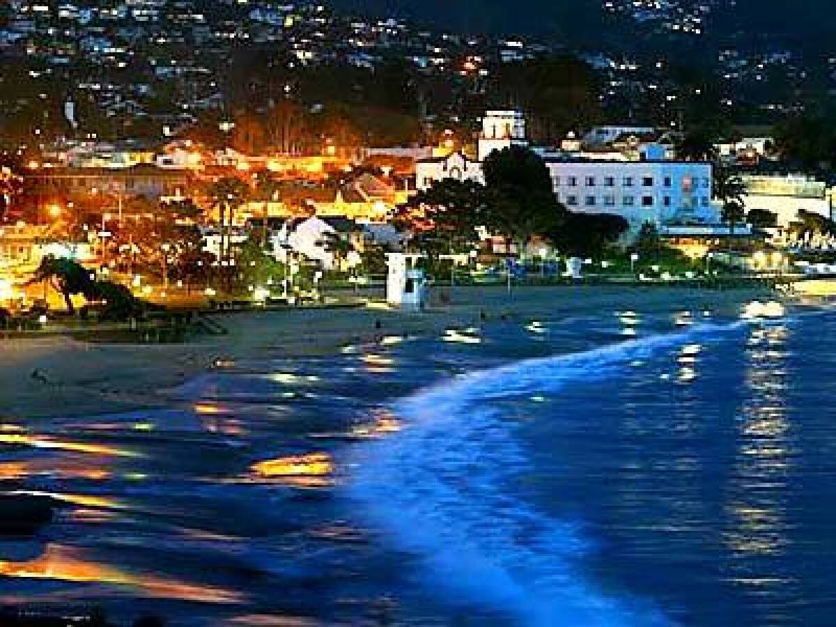 Evening lights shimmer in the hills above town and on the wet sand of Lagunas crescent-shaped main beach.