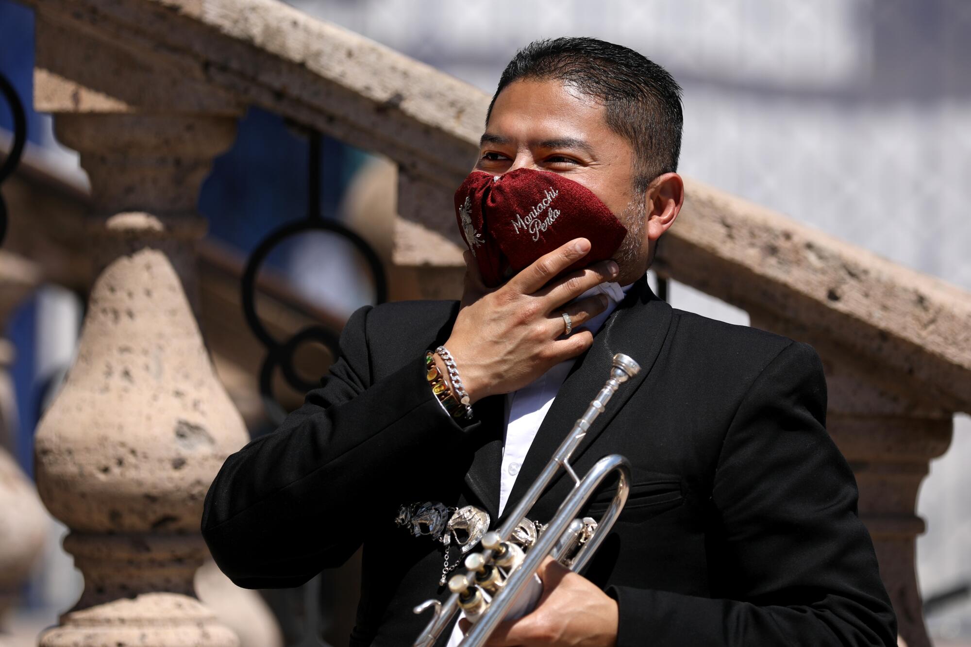 Mariachi Alejandro Bustos uses his tie as a face mask